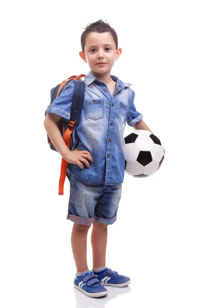 Menino da escola de pé com uma bola de futebol e mochila — Fotografia de Stock