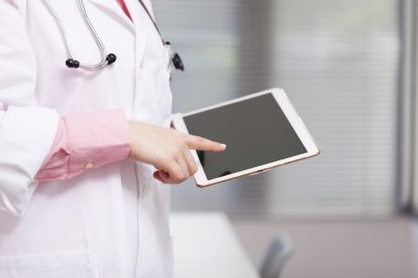 Doktor elinde tablet bilgisayar tutuyor.