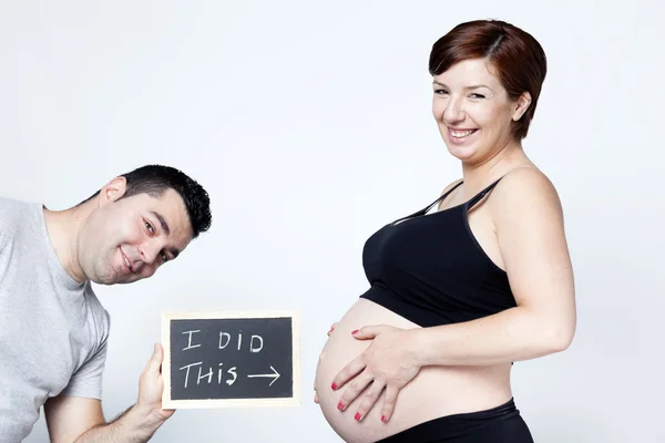 Man hugging his pregnant wife with a blackboard — Stock Photo, Image