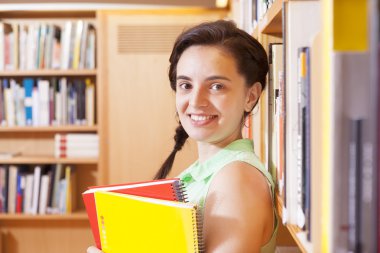 kız öğrenci üniversite kitaplık üzerine eğilerek