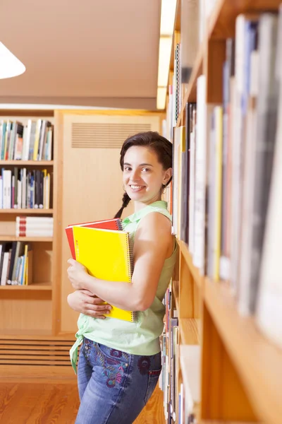 Female student leaning on the bookshelf of the university — Stock Photo, Image