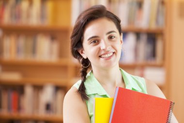 Kütüphanede dizüstü bilgisayarlar ile ayakta kız öğrenci