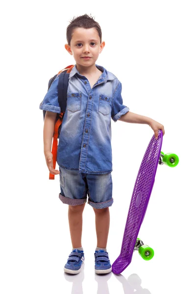 Schooljongen permanent met een skateboard en een rugzak — Stockfoto