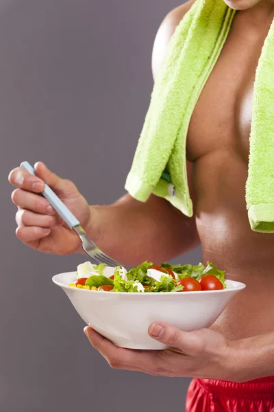 Fit man holding a bowl of fresh salad — Stock Photo, Image