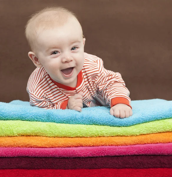 Smějící se děti leží na hromadu barevné ručníky — Stock fotografie