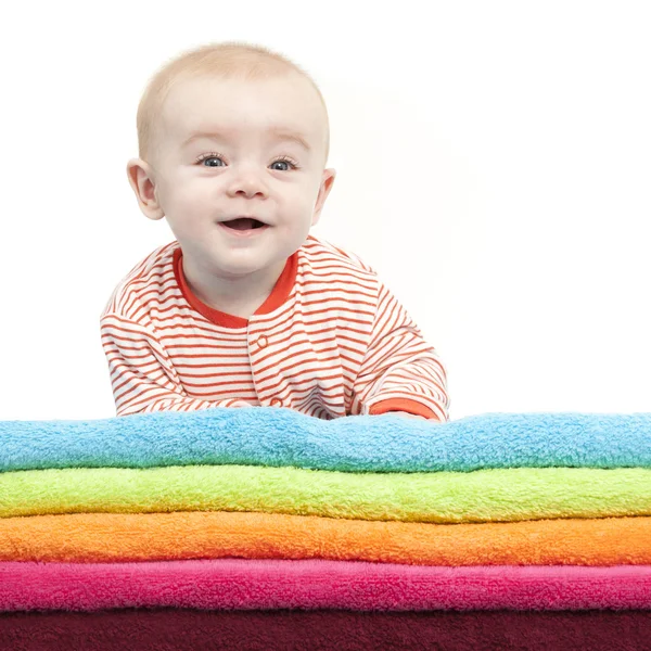 Rindo bebê deitado em uma pilha de toalhas coloridas — Fotografia de Stock