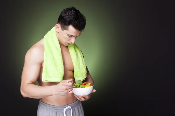 Fitness man holding a bowl of fresh salad — Stock Photo, Image