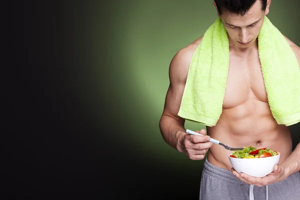 Fitness man holding a bowl of fresh salad — Stock Photo, Image