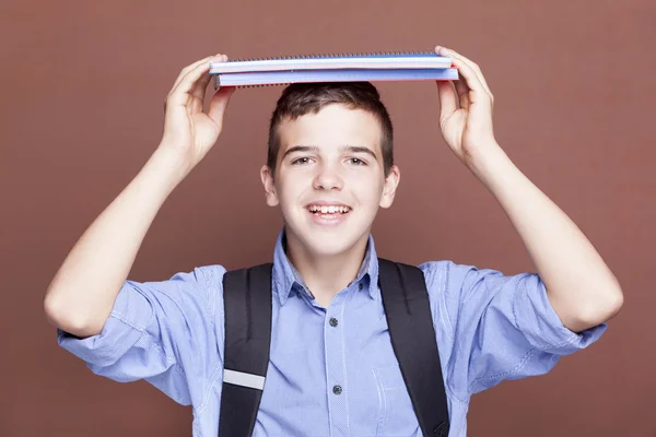 Estudiante masculino sosteniendo libros de texto sobre la cabeza — Foto de Stock