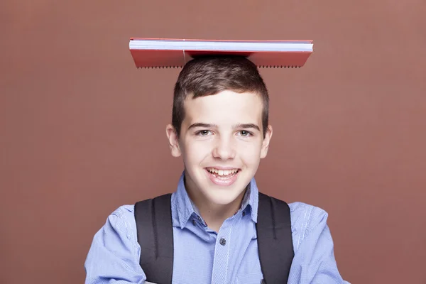 Estudiante masculino sosteniendo libros de texto sobre la cabeza — Foto de Stock