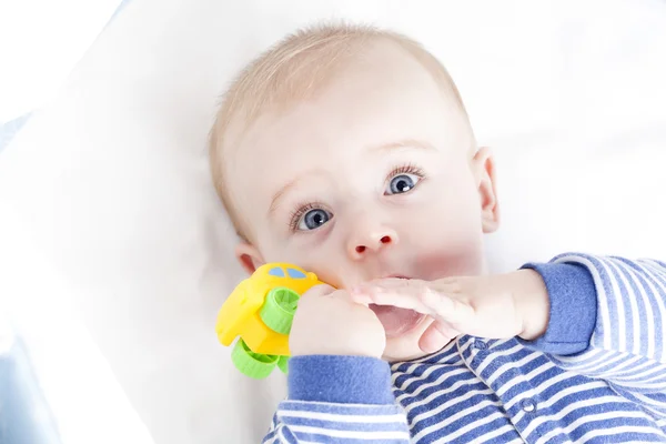 Bebê com olhos azuis brincando com um brinquedo — Fotografia de Stock