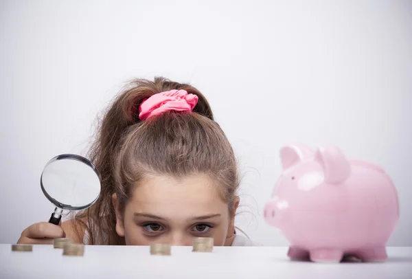 Niña sosteniendo una lupa y mirando al ahorro — Foto de Stock