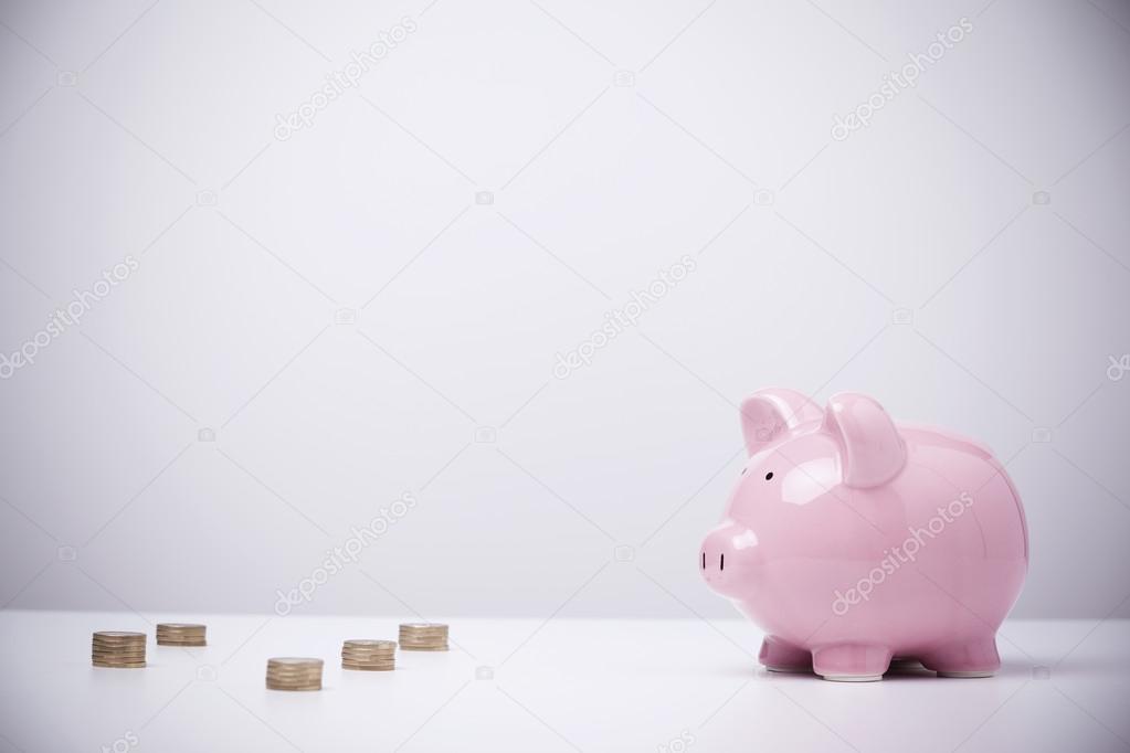 Piggybank and coins on grey background