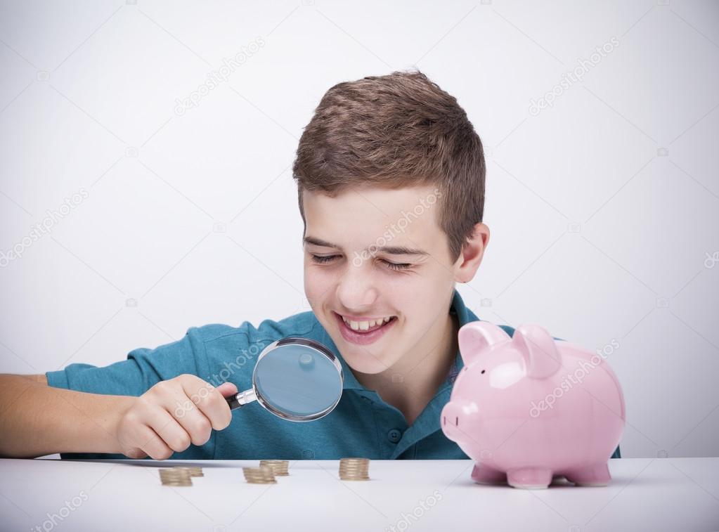 Boy with magnifying glass looking to his savings