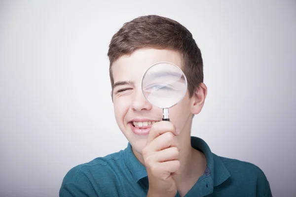 Boy looking through a magnifying glass — Stock Photo, Image