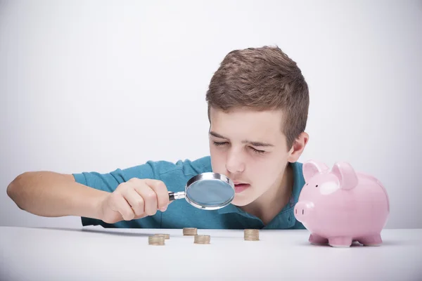 Menino com lupa olhando para suas economias — Fotografia de Stock