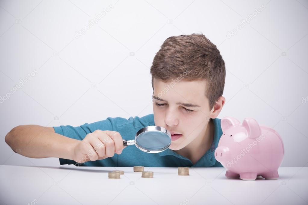 Boy with magnifying glass looking to his savings