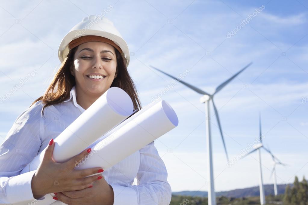 Environmental engineer holding blueprints at wind farm