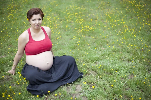 Kobieta w ciąży siedzi i relaks na świeżym powietrzu — Zdjęcie stockowe