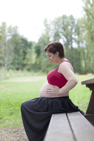 Sitting pregnant woman relaxing outdoors — Stock Photo, Image