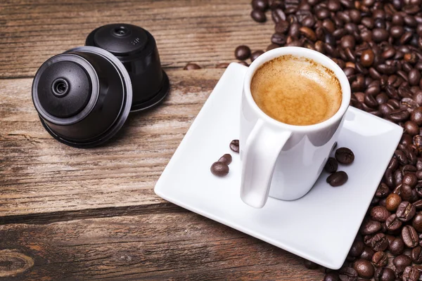 Чашка кофе и стручки на деревянном столе — стоковое фото