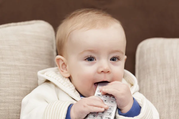 Sorrindo bebê segurando um controle remoto tv — Fotografia de Stock