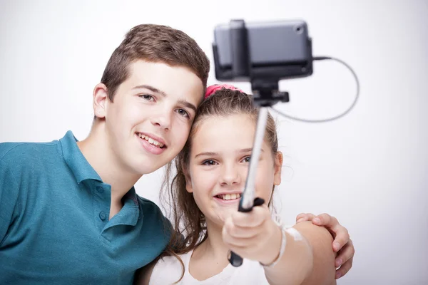 Hermanos tomando una foto con un palo selfie — Foto de Stock