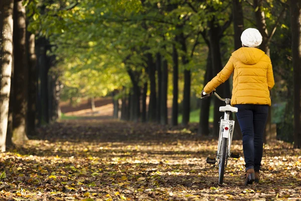 Kvinnan promenader med en vintage cykel på parken — Stockfoto