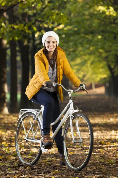 Mujer sonriente de pie con una bicicleta vintage en el parque —  Fotos de Stock