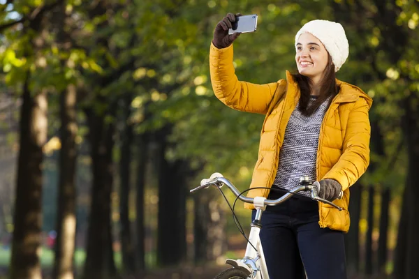 Femme avec son vélo et faire un selfie au parc — Photo