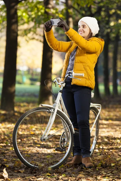 Kvinna med hennes cykel och att göra en selfie på park — Stockfoto