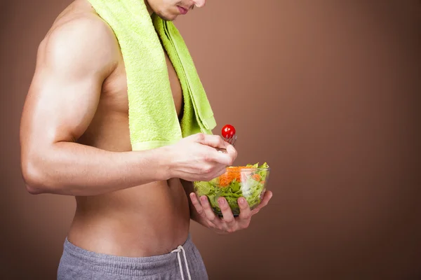 Muskulös man håller en skål med sallad — Stockfoto