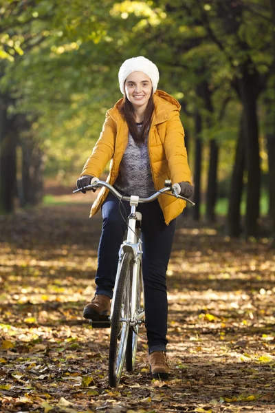 Leende kvinna står med en cykel på parken — Stockfoto
