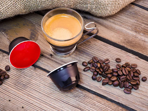 Tasse Kaffee und Pads auf Holztisch — Stockfoto