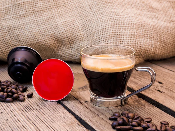 Taza de café y vainas en mesa de madera — Foto de Stock