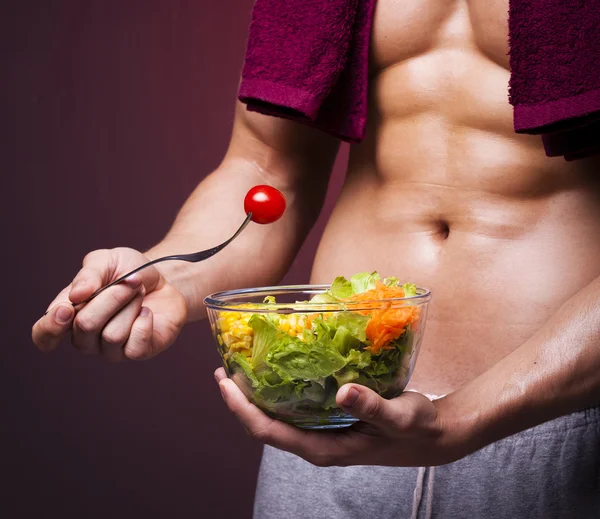 Muskulös man håller en skål med sallad — Stockfoto