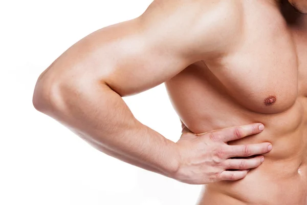 Muscular young man holding his back in pain — Stock Photo, Image