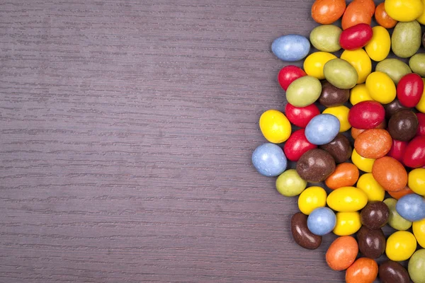 Chocolates coloridos em fundo de madeira — Fotografia de Stock