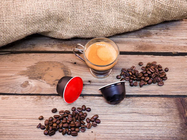 Tasse Kaffee und Pads auf Holztisch — Stockfoto