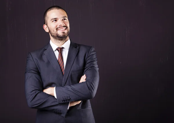 Dreaming businessman standing with arms crossed — Stock Photo, Image