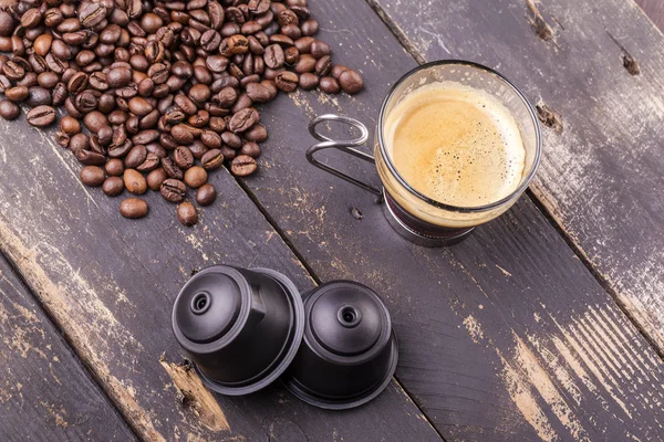 Kaffeetasse und Kapseln auf einem Holztisch — Stockfoto