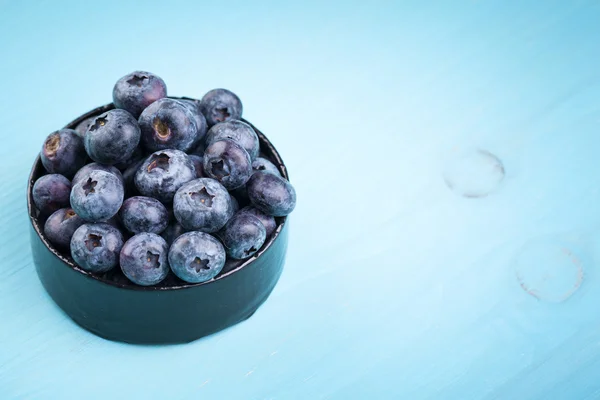 Blueberries in a bowl on a turquoise wooden table — Stock Photo, Image