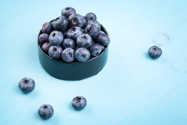 Blueberries in a bowl on a turquoise wooden table — Stock Photo, Image