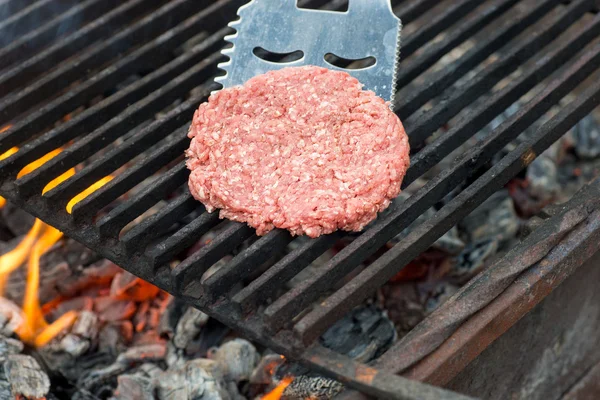 Raw hamburger slice cooking on grill with flames — Stock Photo, Image