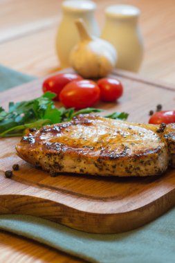 Domuz pirzolası (boyun kesim) kesme tahtası üzerinde sulu ızgara.