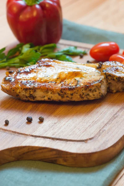 Juicy grilled pork chop (neck cut) on cutting board. — Stock Photo, Image