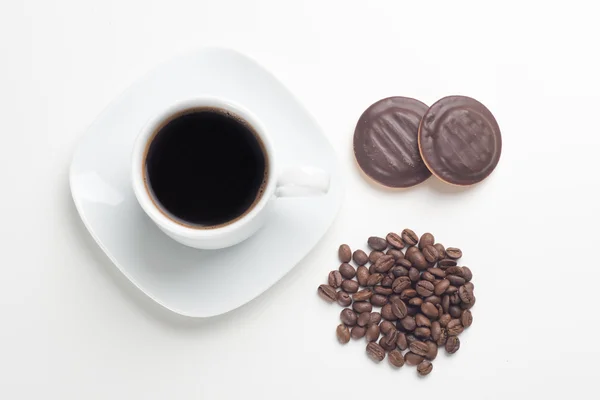Белая чашка, черный кофе, бобы и торты — стоковое фото