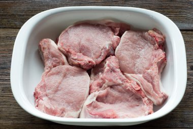 Ahşap masa üzerinde bir tabak içinde çiğ domuz fileto biftek