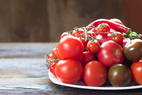 Tomatoes of different kinds on a white dish. — Stock Photo, Image