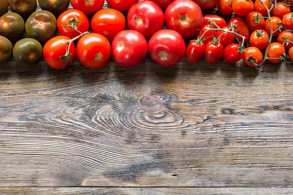 Colorful tomatoes on wooden table background. Top view. — Stock Photo, Image